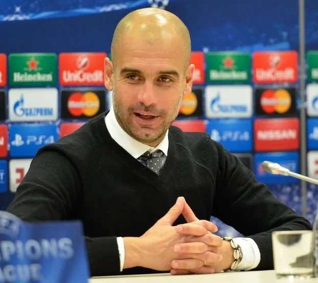 Pep Guardiola seduto in conferenza stampa